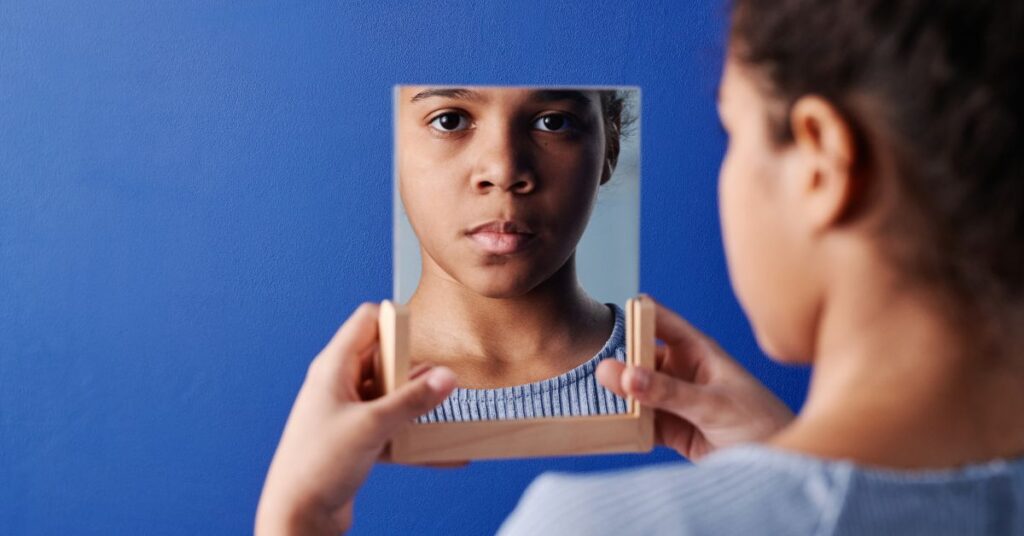 A middle-school aged girl looks in a mirror, Body Image for Kids
