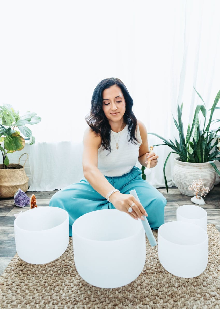 Rachel Andrade, integrative nutrition dietitian and founder of Whole Lifecycle Nutrition, sits at her work desk with plants, self love book, affirmation cards, and journal